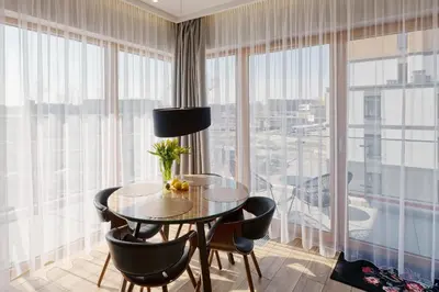 a dining room with a table and chairs and large windows at atHome Suites in Kraków