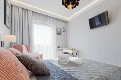 a white bedroom with a bed and a chair at atHome Suites in Kraków