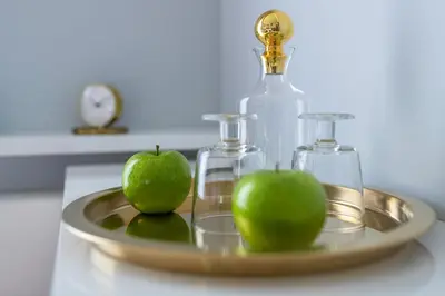 two green apples on a tray with a bottle and glasses at atHome Suites in Kraków