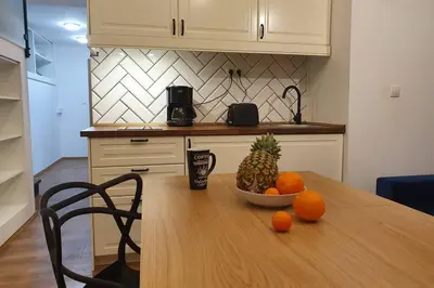 a kitchen with a table with a bowl of pineapple and oranges at Koci Dom Loft in Wieliczka