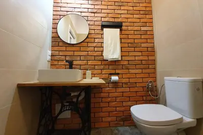 a bathroom with a toilet and a mirror on a brick wall at Koci Dom Loft in Wieliczka