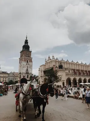 two horses pulling a carriage in a town square at Last Floor Apartment - Krakow City Center close to Old Town in Kraków