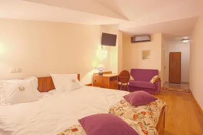 a bedroom with a white bed and a purple chair at Aparthotel Grodzka 21 Self-Check in in Kraków
