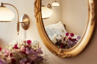 a mirror in a room with a bed and flowers at Aparthotel Grodzka 21 Self-Check in in Kraków