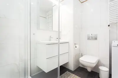 a white bathroom with a toilet and a shower at City of the Kings - Leaf Apartment in Kraków