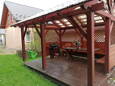 a wooden pergola with a picnic table on a deck at Apartament-studio, pokoje u Lucy in Rabka
