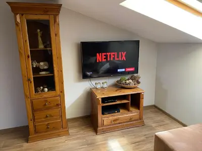 a living room with a television and a wooden cabinet at Bronowicka Premium Apartment - 52m2 with private parking in Kraków