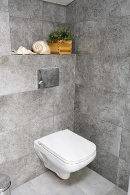 a bathroom with a white toilet in a tile wall at Bronowicka Premium Apartment - 52m2 with private parking in Kraków
