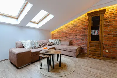 a living room with a couch and a brick wall at Bronowicka Premium Apartment - 52m2 with private parking in Kraków