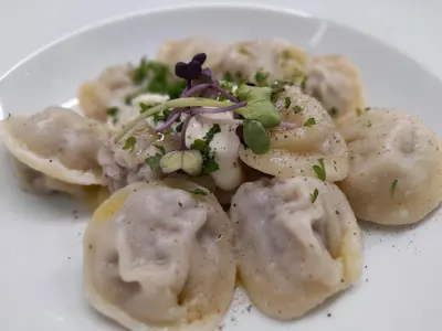 a white plate of food with dumplings on it at Merci Boutique Hotel in Kraków