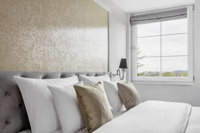 a bedroom with a bed with white pillows and a window at Merci Boutique Hotel in Kraków