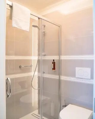 a bathroom with a glass shower with a toilet at Merci Boutique Hotel in Kraków