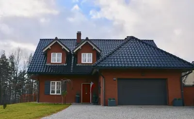 a red brick house with a large garage at Siedlisko Inwałd in Inwałd