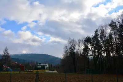 a field with a fence and trees and a house at Siedlisko Inwałd in Inwałd