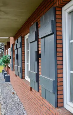 a brick building with black shutters and windows at Siedlisko Inwałd in Inwałd