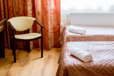 a hotel room with two beds and a chair at Hostel Rest in Kraków