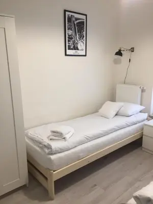 a bed in a room with a white wall at Apartament Kraków Arena No 76 in Kraków