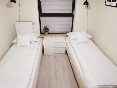 two beds in a small room with a window at Apartament Kraków Arena No 76 in Kraków