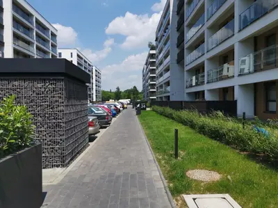 a sidewalk next to a parking lot with parked cars at Apartament Kraków Arena No 76 in Kraków