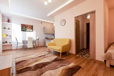 a living room with a chair and a dining room at Piast Apartament in Kraków