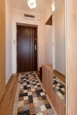 a hallway with a wooden door and a checkered floor at Piast Apartament in Kraków