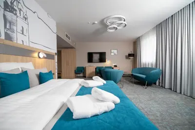 a hotel room with two beds and blue chairs at Krowodrza Centrum Konferencyjno - Hotelowe in Kraków