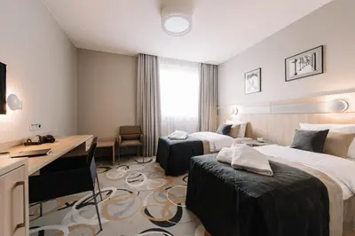 a hotel room with two beds and a desk at Krowodrza Centrum Konferencyjno - Hotelowe in Kraków