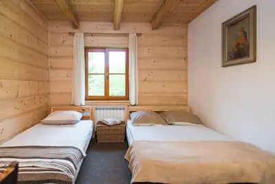 two beds in a room with wooden walls at Amigówka in Wieliczka