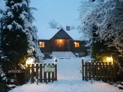 a house with a gate in the snow at night at Amigówka in Wieliczka