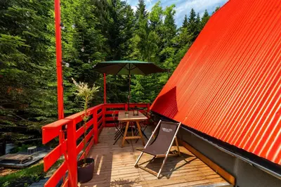 a wooden deck with a table and an umbrella at Zawoja 1725 - Slow Life Cabins in Zawoja