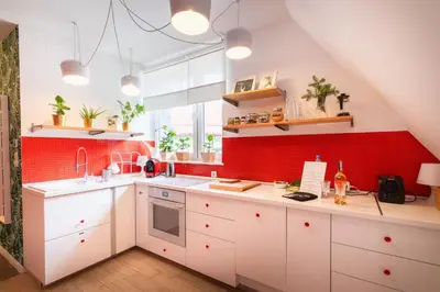 a kitchen with white cabinets and a red wall at Zawoja 1725 - Slow Life Cabins in Zawoja