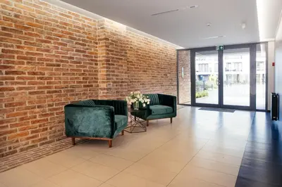 a lobby with two chairs and a brick wall at Way2Stay Rakowicka in Kraków