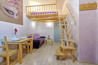 a small room with a loft bed and a table and a desk at Libro Rooms in Kraków