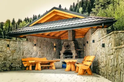 a pavilion with a picnic table and a stone wall at Cztery Pliszki in Zawoja