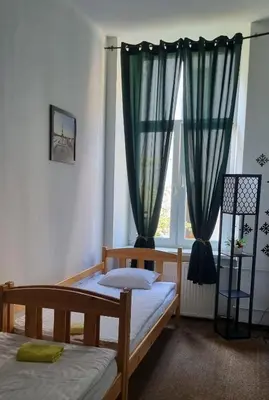 a bedroom with two beds and a window at Green Cat Rooms in Kraków