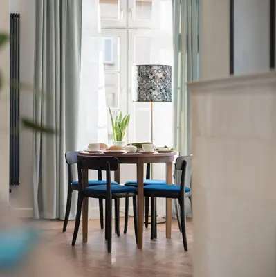 a dining room table with blue chairs and a window at Starowislna 77 in Kraków