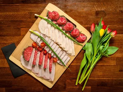 a wooden cutting board with meat and strawberries and flowers at Park Apartamenty Chrzanów in Chrzanów