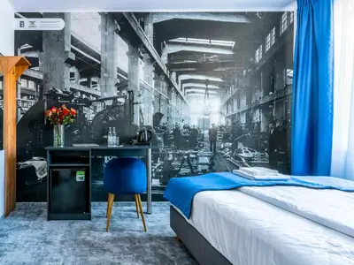 a bedroom with a bed and a desk with a blue chair at Park Apartamenty Chrzanów in Chrzanów