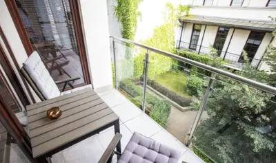 a balcony with a wooden bench and a view of a building at Royal Parkside in Kraków