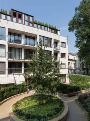 a large white building with a tree in front of it at Royal Parkside in Kraków