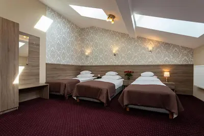 a room with three beds in a room at Hotel Maximum in Kraków