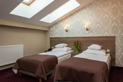 two beds in a hotel room with a skylight at Hotel Maximum in Kraków