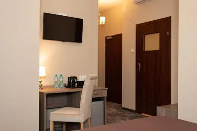 a hotel room with a desk and a television on the wall at Hotel Maximum in Kraków