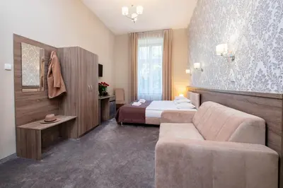 a hotel room with a bed and a couch at Hotel Maximum in Kraków