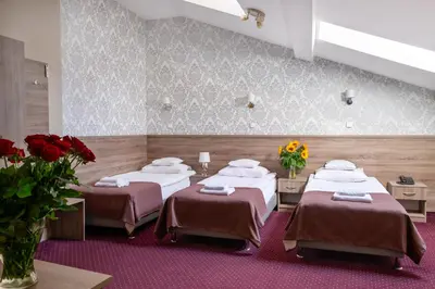 three beds in a room with flowers on the wall at Hotel Maximum in Kraków