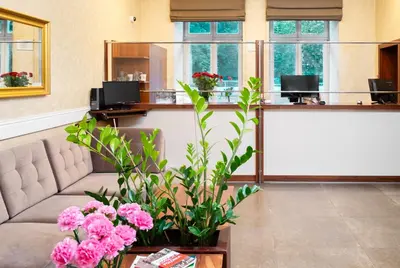 a lobby with a waiting room with pink flowers at Hotel Maximum in Kraków