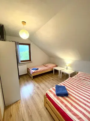 a attic bedroom with two beds and a window at Domek przy Gościńcu in Golczowice