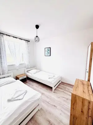 two beds in a room with white walls and wooden floors at Apartament Salton in Bochnia
