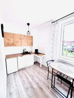 a kitchen with white cabinets and a table and a window at Apartament Salton in Bochnia