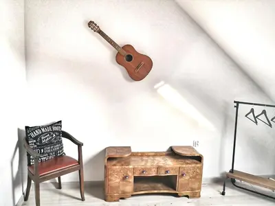 a guitar on the wall next to a chair and a trunk at Lawenda i Bluszcz in Jankowice